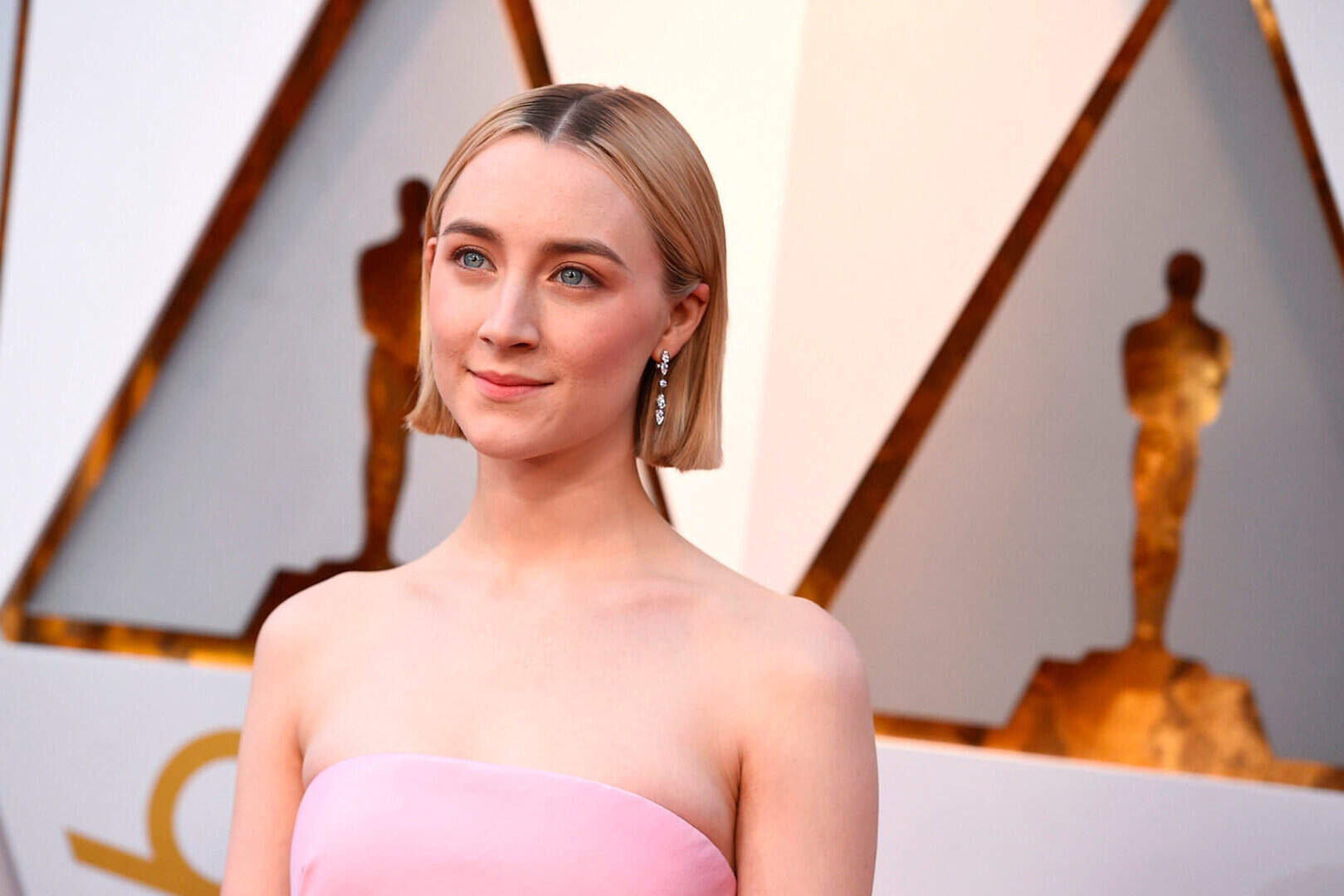 saoirse ronan pink dress Saoirse Ronan looks effortlessly elegant in this soft blush pink strapless  gown, featuring a clean, minimalist silhouette that flows beautifully. The  oversized bow detail at the back adds a touch of playful